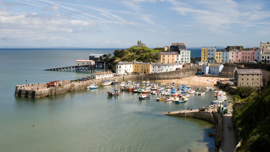 Harbour with boats in the water and a row of colourful houses on land - Tenby- great walks in Wales