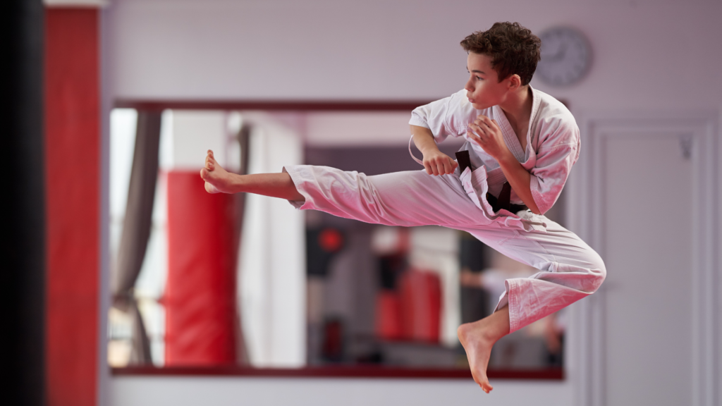 Teenage boy doing a jumping kick in karate uniform