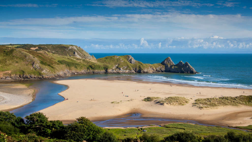 Large sandy beach with green cliffs and blue skies